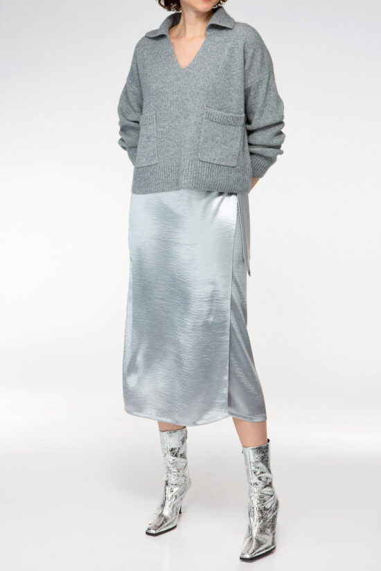 IVI collection figurbetonter Wickelrock aus einem schimmernden Metallic-Effekt Stoff in Farbe silber aus der AW24 Kollektion. Kombiniert mit grauen Strickpullover und silbernen Stiefeln. IVI collection figure-hugging wrap skirt made from a shimmering metallic-effect fabric in silver from the AW24 collection. Styled with grey knit sweater and silver boots.
